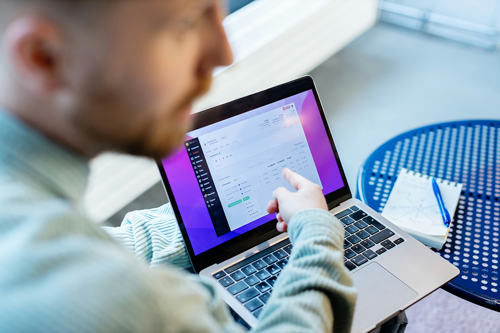Image showing blurred man in the foreground pointing at a laptop screen showing project management software